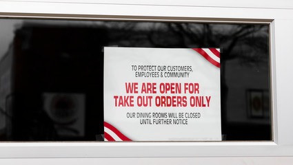 Open for take out orders only sign in window of restaurant
