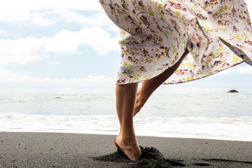 Side of woman turning with dress on sand by beach