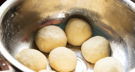 dough balls in a stainless steel bowl for making dhal puri 
