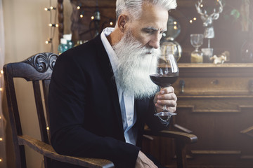 Handsome bearded senior man drinking red wine