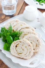 Sliced baked chicken breast roll with garlic on a white dish, selective focus