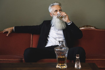 Handsome bearded senior man drinking whiskey