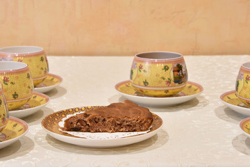 Homemade pie with berries and cups with saucers on the table