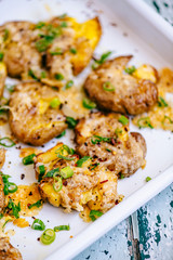 Cheesy Crushed Potatoes with spring onions in a white enamel tray