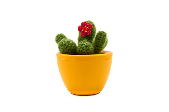 Gr&uuml;ner handgearbeiteter Kaktus ( cactus Gymnocalicium ) in einem gelben Blumentopf aus Ton mit roter Stoff Bl&uuml;te und brauner Erde, von vorne ab gelichtet