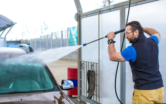 A Man Washes A Car With Water Under Pressure.