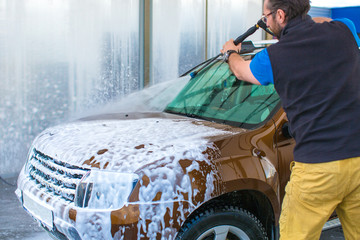 A man washing a car with water under pressure.