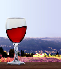 A glass of red wine in front of French alps and lavender fields. A tilt has been added for more dynamic.