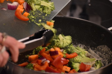 A close up of chopped mixed vegetables being put into a frying pan
