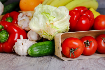 Against the background of a light countertop, tomatoes, cucumber, red pepper, garlic, iceberg salad.