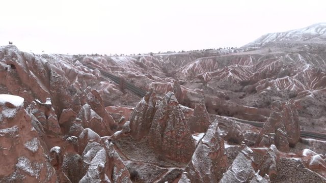Fairy chimneys and cave houses surrounded by rock formations at Imaginary Valley in Cappadocia, Turkey. Tufa formations covered with snow in Devrent Valley in Cappadocia