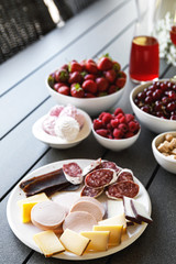 Table full of snacks. Cheese, sausage, salami, meat and berries..