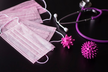 Coronavirus concept. Medical pink masks, stethoscope  and viruses on a black background.