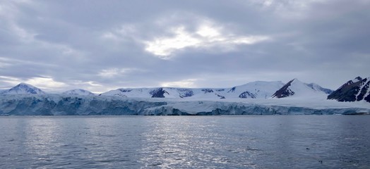 Glacier front in antarctic sea with cloudy sky, dark ocean, Antarctica