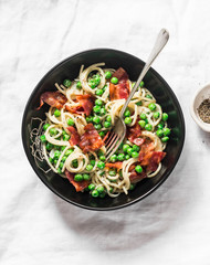Spaghetti with crispy ham and creamy green peas on a light background, top view