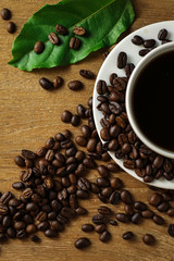 White coffee cup and coffee beans on wooden table with copyspace for text. Selective focus.