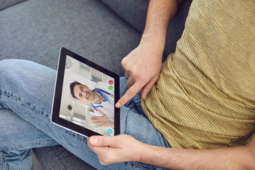 Online doctor. A man talks to a doctor using the video call application for a medical consultation...