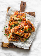 Mustard, lemon, thyme marinade baked chicken wings on wooden chopping board - delicious appetizers,...