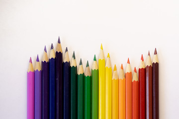 set of colored pencils on a background laid out by a rainbow