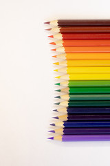 set of colored pencils on a background laid out by a rainbow