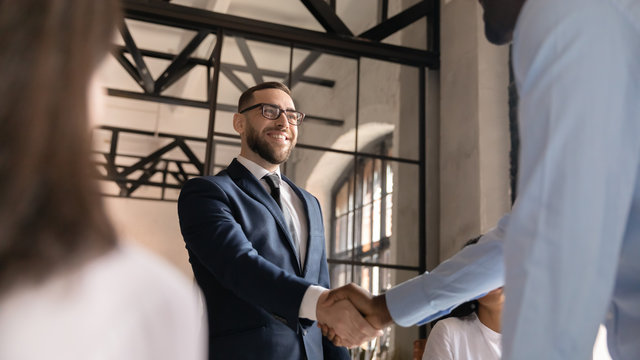 Smiling middle-aged businessman shake hand of male colleague get acquainted or greeting at meeting, happy male employee handshake coworker congratulate with promotion, acquaintance concept - Powered by Adobe