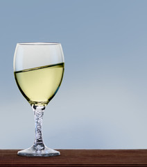 Glass of white wine on neutral background. A tilt has been added for more dynamic.