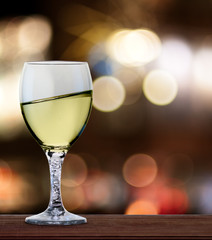 A glass of white wine in front of blured city lights. A tilt has been added for more dynamic.