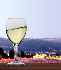 A glass of white wine in front of French alps and lavender fields. A tilt has been added for more dynamic. 