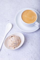 Homemade ice cream with chocolate chips in a bowl. One ball of ice cream and a cup with coffee. Close-up.