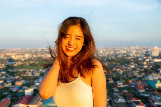 Portrait pretty young asian woman. Attractive beautiful girl stand on top of building for seeing nice view and looks beautiful sunset. Charming female get happiness with smiley face in summer time.