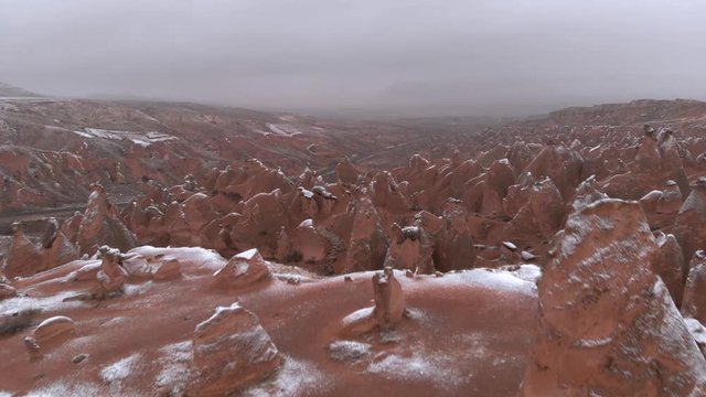 Fairy chimneys and cave houses surrounded by rock formations at Imaginary Valley in Cappadocia, Turkey. Tufa formations covered with snow in Devrent Valley in Cappadocia