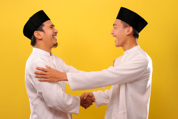 Image of happy two Young Asian Muslim men celebrate victory day, Eid Al-Fitr 2020M/1441H with shaking hand and smile each other
