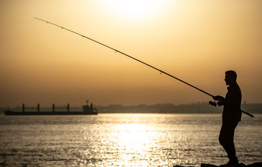 Fisherman at Bosphorus strait in Istanbul, Turkey during sunset