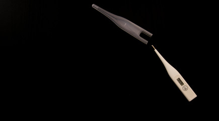 white thermometer with high temperature on a black background isolate