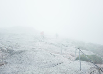 Dangerous and foggy hiking route with metal chain in Norwegian mountains