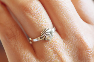 Fototapeta premium Hand wearing elegant silver ring in the shape of the shell