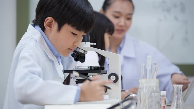 Asian children or student viewing object very small with microscope in classroom at modern laboratory. Schoolboy and Schoolgirl studies subject science. Concept of education, science, technology.