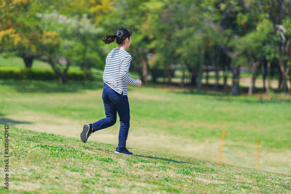 Wall mural Japanese young woman running at park in spring