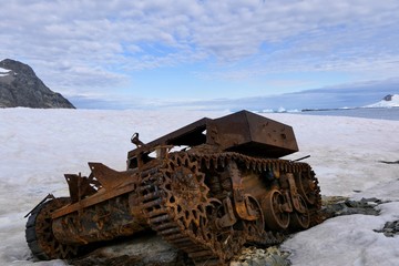 Rusty tank wreck in Antarctica, at Stonington Island east base, on snow with mountain in background