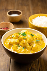 Chicken curry with parsley in bowl on wooden table