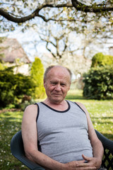 Portrait of senior man sitting in chair at his garden