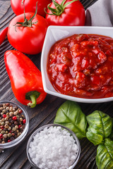Fresh tasty tomato sauce on rustic wooden background