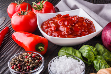 Fresh tasty tomato sauce on rustic wooden background