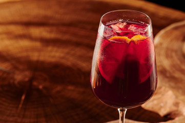 Red sangria in a glass on a wooden background. Traditional span alcoholic drink with red wine, fruits and ice on a wooden background. Close-up.