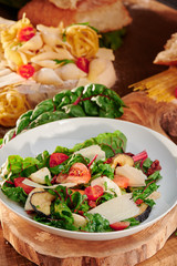 Vegetarian Salad with tomatoes, mozzarella, parmesan and fried eggplant on a wooden background. Traditional italian salad. Close-up.