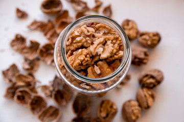 Whole walnuts in a jar. Walnuts on a white cutting board