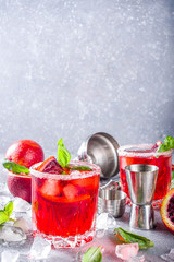 Skinny blood orange basil lemonade cocktail, with fresh bloody oranges, basil leaves and vodka, Grey stone concrete background flat lay copy space