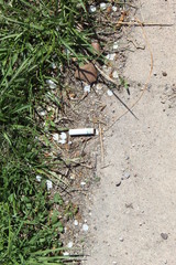 Obraz premium Cigarette butt thrown in near grass on sidewalk