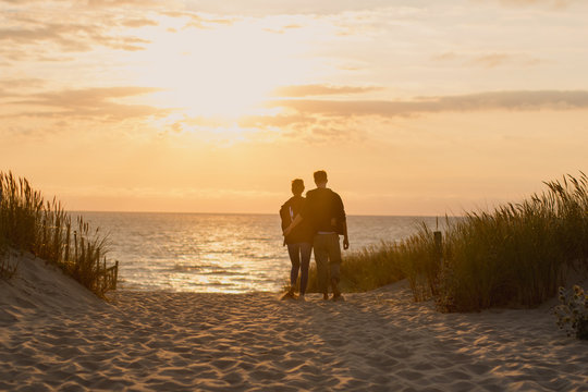 Pareja enamorada caminando hacia la playa para ver la puesta de sol durante sus vacaciones.