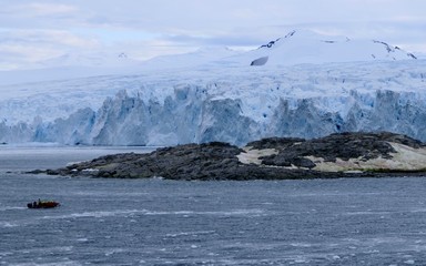 Tender boat landing at Stonington Island east base with glacier in background and dark ocean, Antarctica